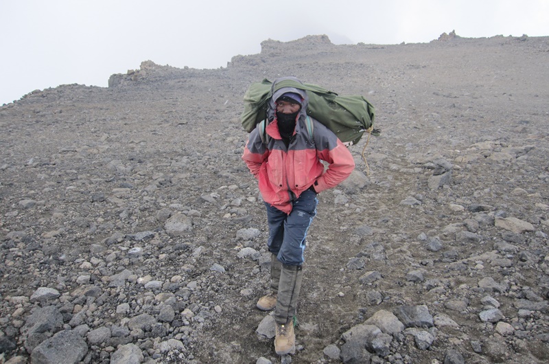 After passing through Western Breach, a porter takes a pause in the crater of Kilimanjaro.